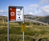 Signs on the way to Derrick Hut with Mount Hotham village in the distance