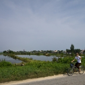 Lisa riding her bike next to the rice paddies between Hoi An and Cua Dai Beach