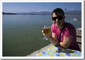 Lisa knocking back an Efes with bread-hungry fish in the water behind her