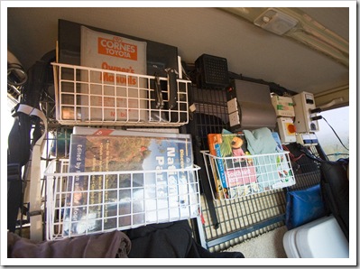 Book racks (times three), a two-output pure sine wave inverter, the little black box at the top is the speaker for the HF radio, solar controller top right and the red knob is the on/off switch for the solar panels