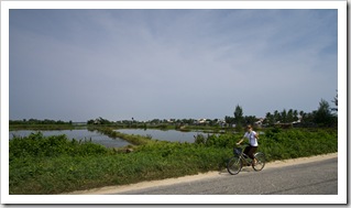 Lisa riding her bike next to the rice paddies between Hoi An and Cua Dai Beach